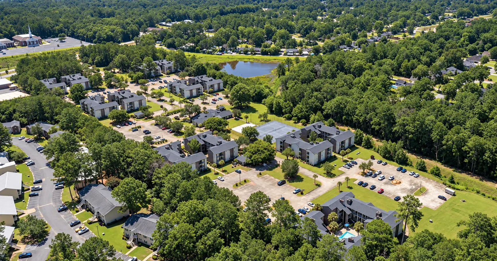 Aerial view of the Albany apartment community with landscaped grounds, tennis courts, and a pool